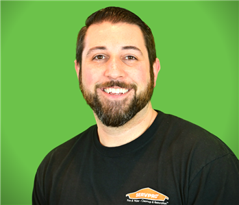 A male SERVPRO employee smiles infront of a green background.