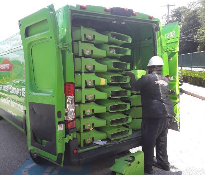 SERVPRO Tech loading up green equipment into a SERVPRO vehicle.